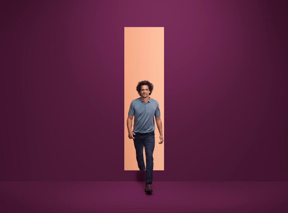 A young professional walking through an aubergine-colored doorway