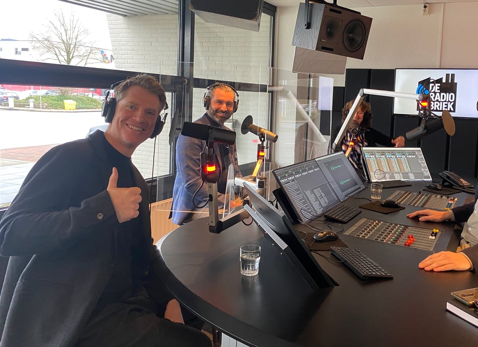 Deelnemers nemen in een radiostudio de Relevance-lanceringspodcast van 2022 op.