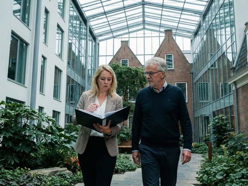 Zwei Kollegen im Gespräch auf dem Weg durch ein helles Atrium