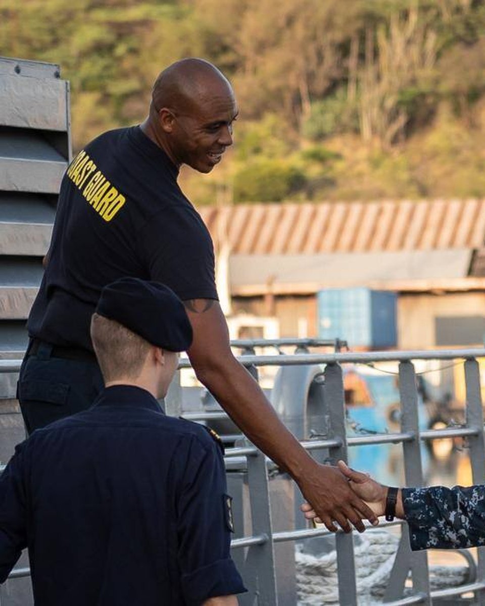 Two service members shaking hands on deck